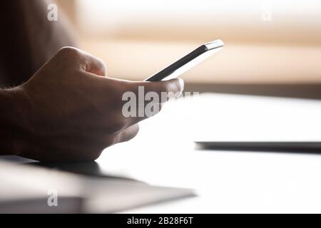 Close up focus on smartphone in african american male hands. Stock Photo