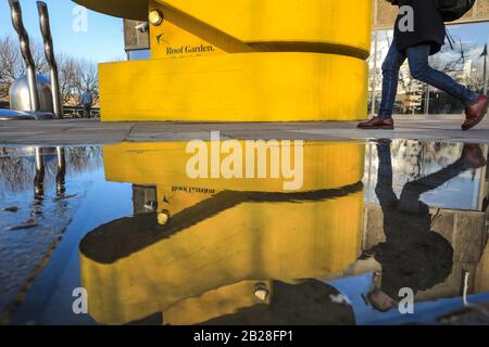 London, UK. 1st Mar, 2020. Visitors to London's Southbank Centre are reflected in rain puddles as they walk past one of the centre's iconic bright yellow brutalist architecture staircases. The day in London saw beautiful sunshine with blue skies, in stark contrast to Saturday's rain and storm. Credit: Imageplotter/Alamy Live News Stock Photo