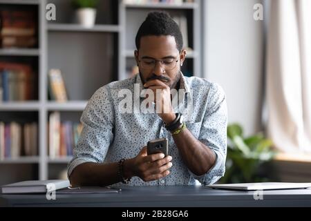 Focused millennial businessman checking email in mobile application. Stock Photo