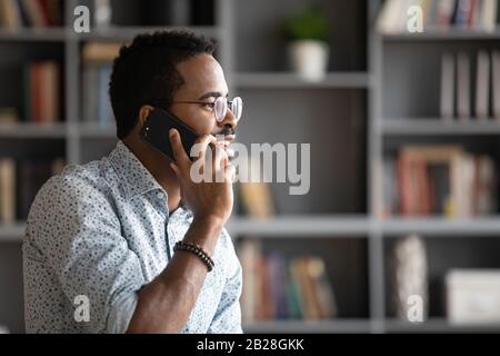 Pleasant handsome biracial man in glasses talking on phone. Stock Photo