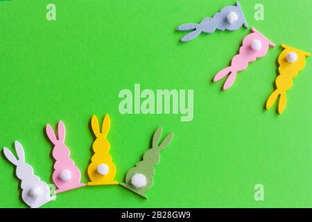 garland of wooden colorful rabbits on green background for ester holiday. Stock Photo
