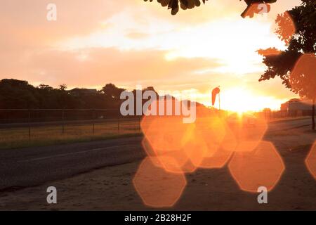 Hexagonal bokeh illuminated bright orange from the rays of sun from a most alluring sunset on a cloudy day over the Vigie Airport Stock Photo