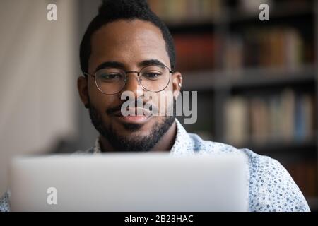 Close up focused young african ethnicity man working on computer. Stock Photo