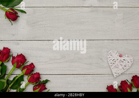 Romantic background, white wooden planks with natural red roses and white heart for concepts, posters or design. Stock Photo