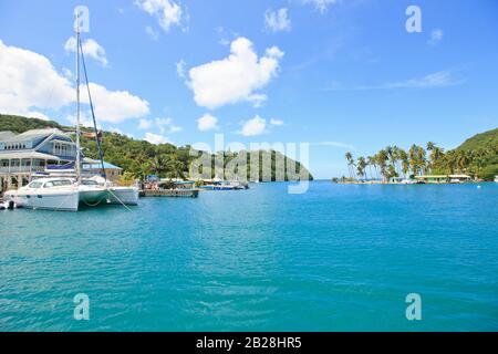 Beautiful blue sea water at Rodney Bay Marina with white catamarans, yachts ,small boat green landscape on a bright day in sunny tropical Saint Lucia Stock Photo