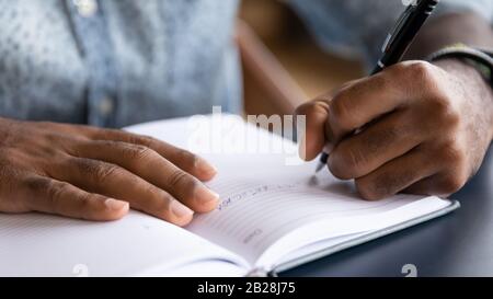 Close up young mixed race guy writing down notes. Stock Photo