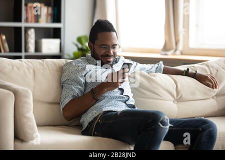 Smiling young biracial man using mobile applications. Stock Photo