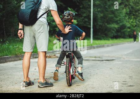 father teaching son how to ride bicycle Stock Photo