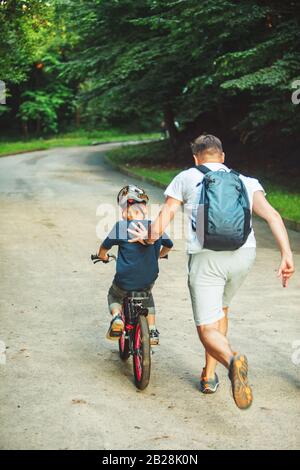 father teaching son how to ride bicycle Stock Photo