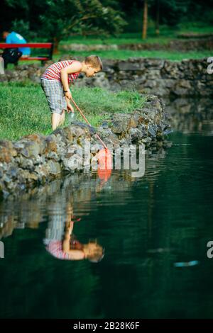 Lviv, Ukraine - June 23, 2019: kid with fish net looking tadpole in