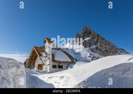 Chapel at Passo Falzarego (Falzarego Pass) and Sass de Stria mountain in winter, Dolomites, Veneto, Italy Stock Photo