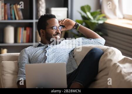 Multiracial freelance guy distracted from job study, looking at window. Stock Photo