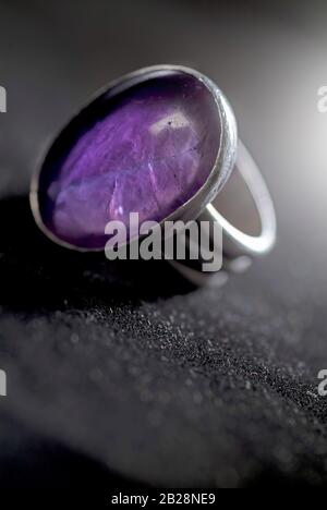 silver ring with a purple stone on dark background Stock Photo