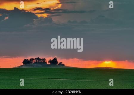 Dynamic sunset among the clouds over the Owyhee Mountain Rage with high desert terrain on the other side of the barbed wire fence in the foreground Stock Photo