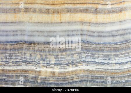 The texture of beige marble with wavy gray, brown and beige horizontal stripes. Polished surface. Stock Photo