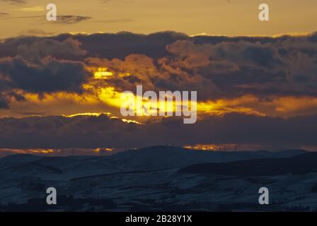 Winter sunset over the Ochil hills, which have a wind farm on their upper slopes. Stock Photo