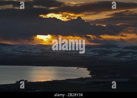 Winter sunset over Loch Leven and the Ochil hills, which have a wind farm on their upper slopes. Stock Photo