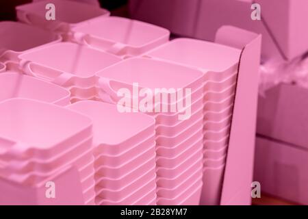folded pink transparent plastic containers.plastic bowls.Plastic food containers, baskets on the shelf in the store Stock Photo