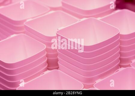 folded pink transparent plastic containers.plastic bowls.Plastic food containers, baskets on the shelf in the store Stock Photo