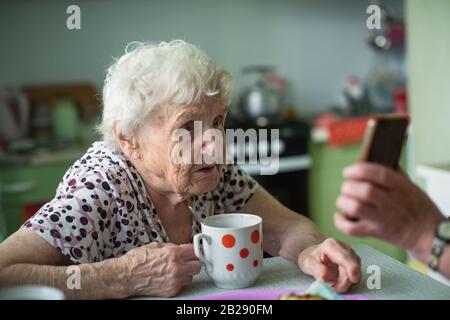 An old woman is shown a smartphone screen. Stock Photo