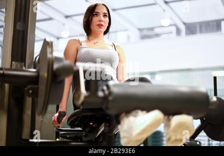 Gym seated leg curl machine exercise woman in the gym Stock Photo