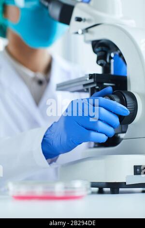 Close up of female scientist using microscope while working on research in medical laboratory Stock Photo