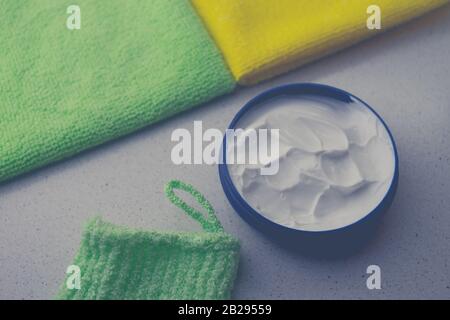 Opened round container with white cream on a table with towels Stock Photo