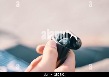 Bishkek, Kyrgyzstan - October 10, 2019: Man holding a custom black airpods from apple Stock Photo