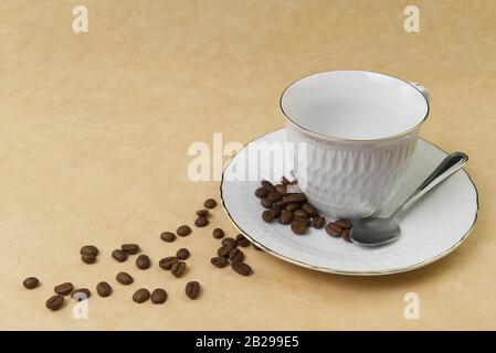 Empty white coffee cup with gold border and coffee seeds on the table. close up Stock Photo
