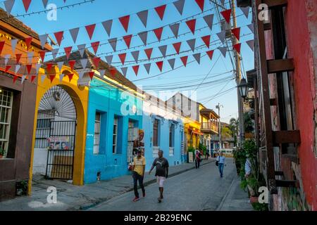 People walking past colorful houses in the Barrio Getsemaní neighborhood, Cartagena, Colombia Stock Photo