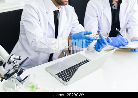 Team of scientist research are working in laboratory / Male doctor researcher are doing investigations with microscope and laptop in lab biochemistry Stock Photo