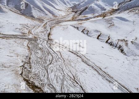 the gravel road on dry land with the snow mountain Stock Photo