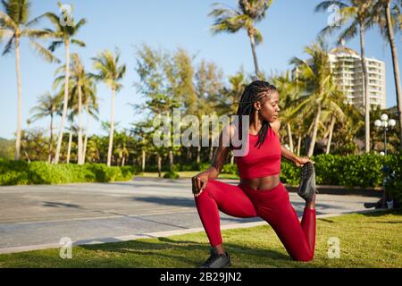 Black fit young woman working out and doing exercise to stretch quadriceps Stock Photo