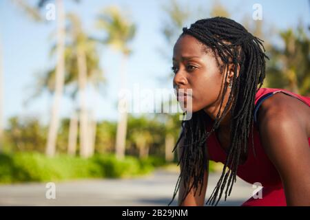 Determined Black sportswoman with dreadlocks looking forward when standing in starting position Stock Photo