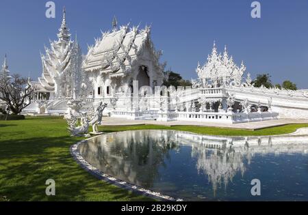 White Temple Ice Palace Exterior and Natural Park in Famous Wat Rong Khun Buddhist Complex, Chiang Rai Province, Thailand Stock Photo