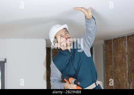 house renovation worker checking the alignment of a ceiling Stock Photo