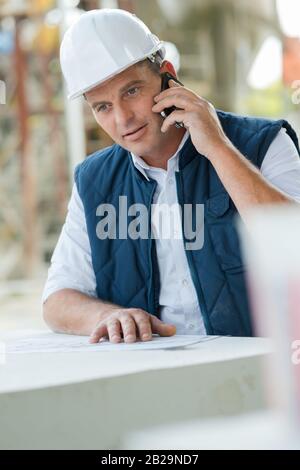 builder on site using mobile phone Stock Photo