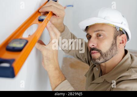 mature male builder using spirit level Stock Photo
