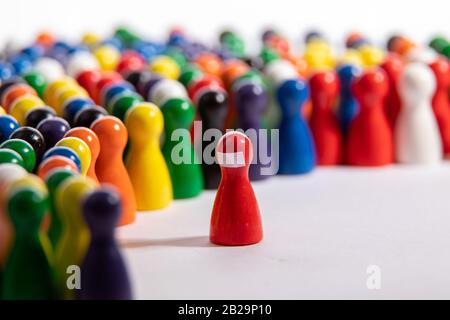 wooden figurine in front of group, standing for speaker before his audiance, wearing a face mask, mouth protection Stock Photo