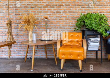 A yellow leather sofa on tile floor and red brick wall background. Stock Photo