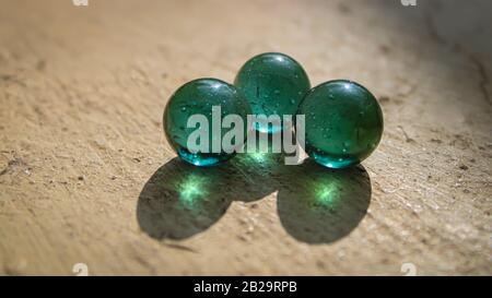 A transparent glass with green marbles on the top of the wall with a good blur background with a creative concept and  text area space Stock Photo
