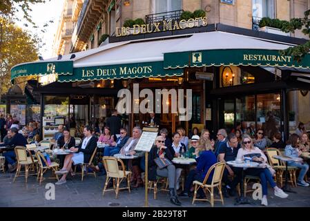 People having coffee at outdoor seating of Les Deux Magots, a famous café in Paris, France Stock Photo