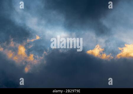 Fluffy clouds illuminated by disappearing rays at sunset and dark thunderclouds floating across sky to change season weather. Stunning view natural Stock Photo