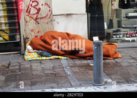 Homeless person sleeping on a street pavement, Athens, Greece, November 22 2019 Stock Photo