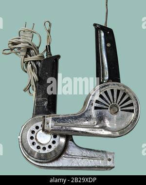 Vintage chrome plated metal hair dryer with black plastic handle on isolated green background with clipping path. Stock Photo