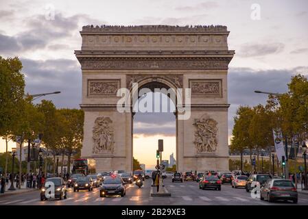The traffic at sunset time in front of Arc de Triomphe, one of the most famous landmark in Paris, France