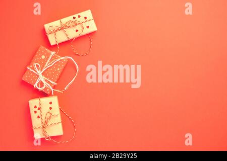 Three craft gift boxes on a red background. Place for text. Holiday and valentines day concept. Flat lay. Stock Photo