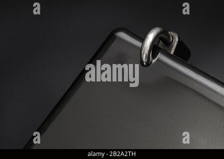 Locked steel padlock in a drilled hole of the black laptop on dark background. Concept of protecting personal data on a computer. A laptop is locked w Stock Photo