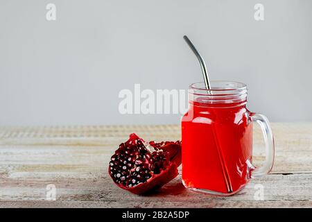 Mason jar with healthy pomegranate juice and fresh pomegranate on the wooden background. Zero waste concept. Metal straw in jar. Copy space Stock Photo