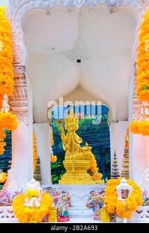 Golden multi-faced buddha statue in a shrine with orange flowers, Bangkok, Thailand Stock Photo
